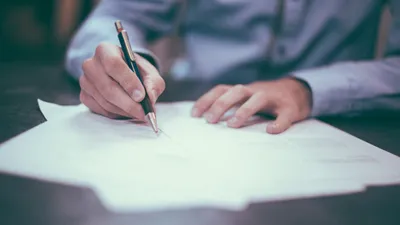 Person reviewing roofing contract documents to avoid scams
